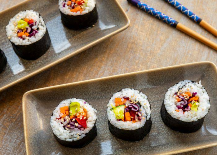 Two servings of vegan sushi rolls, filled with colorful veggies.